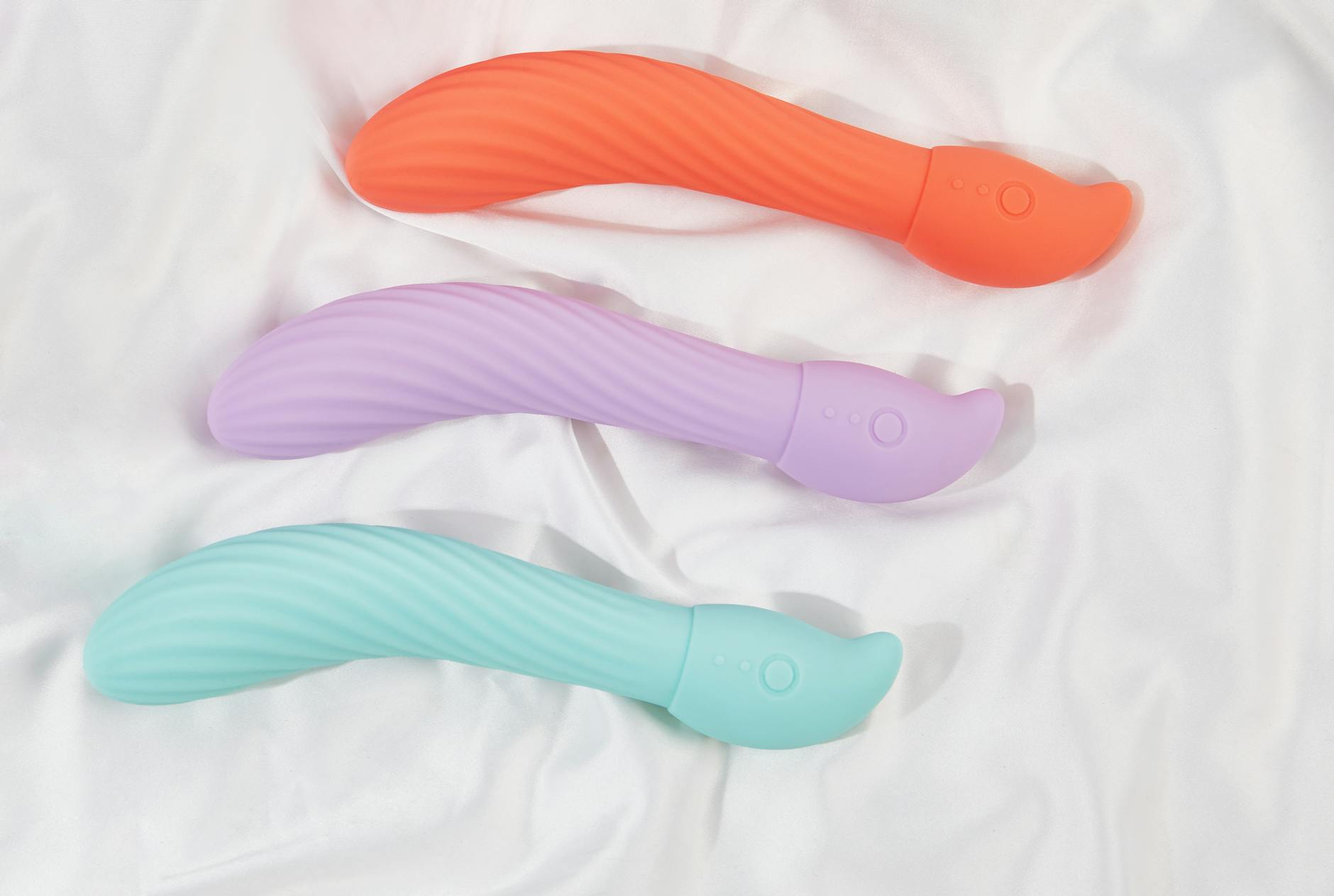 Three colorful lemon vibrators and clitoral toys arranged on soft white fabric