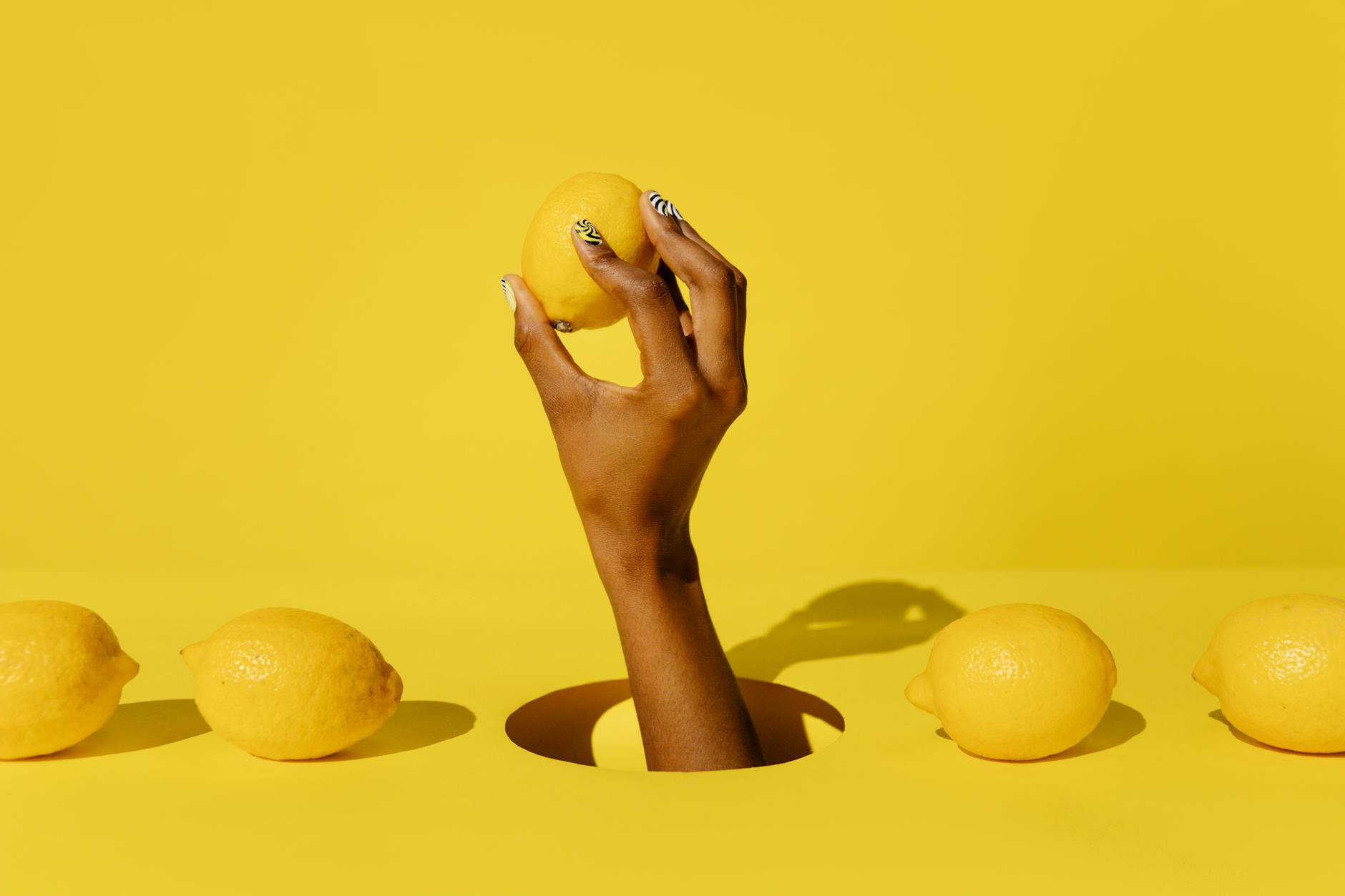 A hand holding a fresh lemon against a vivid yellow background, symbolizing natural, patient recovery