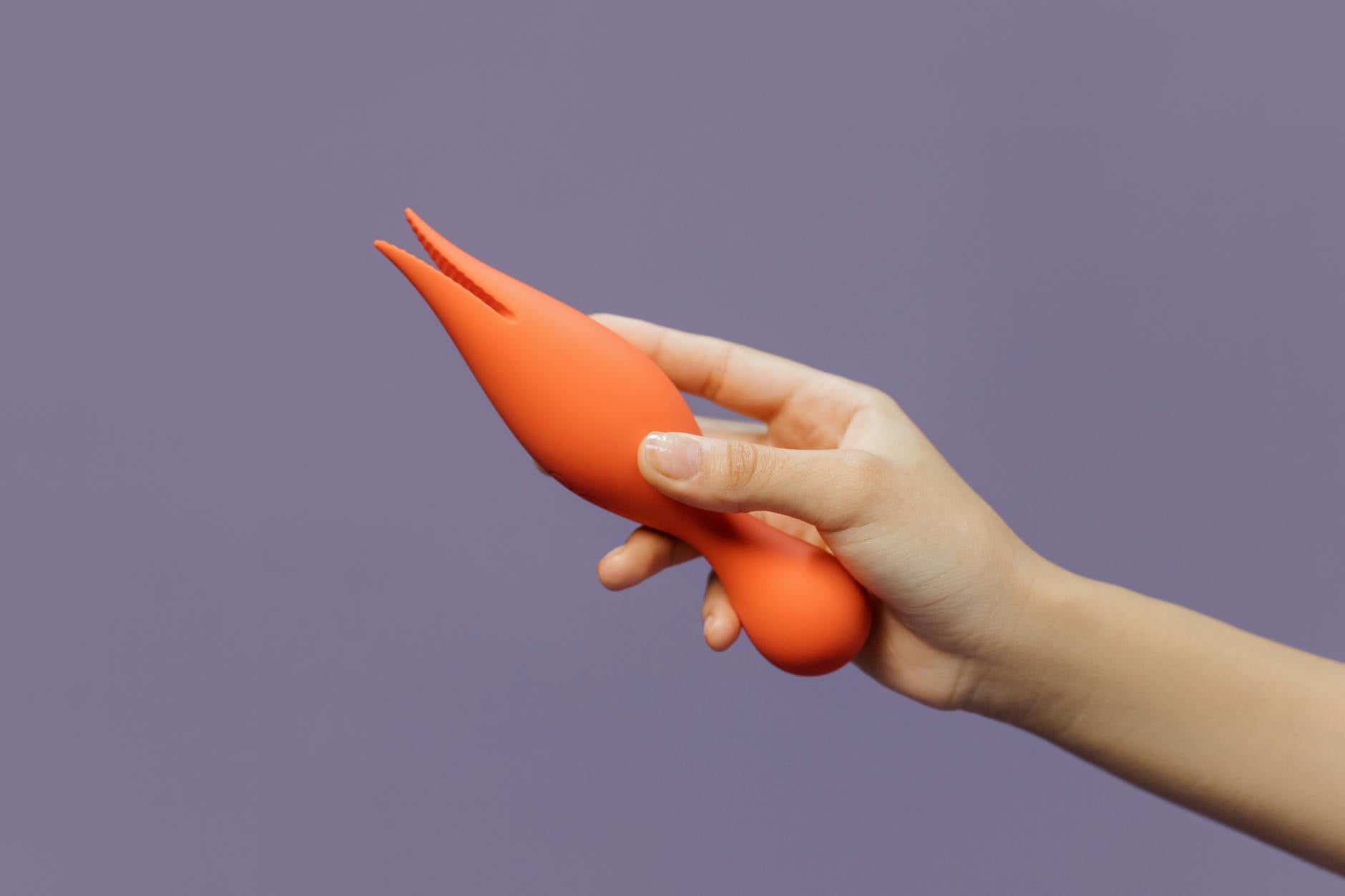 A hand holding a yellow lemon vibrator against a minimalistic purple backdrop, symbolizing modern intimacy and solo pleasure.